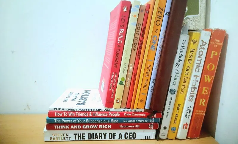 A shelf of the books behind the advice, among them Zero to One, The Psychology of Money, Atomic Habits, The 48 Laws of Power and The Diary of a CEO.